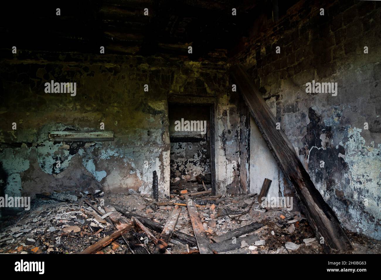 Ein verlassenes Gebäude, das nach einem Brand abgerissen werden muss, mit rußigen Wänden und einer eingestürzten Dielendecke. Stockfoto