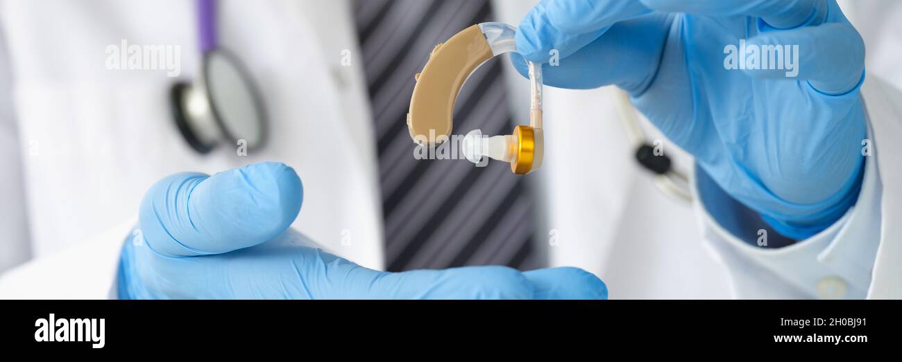 Otorhinolaryngologe, der Hörgeräte mit Gummihandschuhen in der Nähe hält Stockfoto