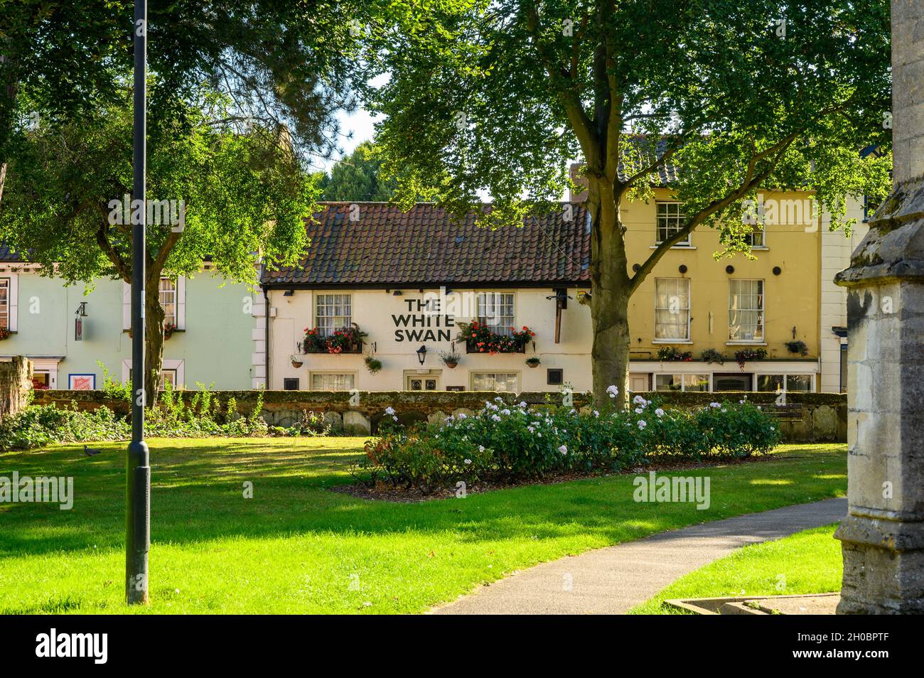 Blick auf die St. Nicholkirche und den Kirchhof zur Church Street mit dem White Swan Pub und dem Heilsarmee-Haus in North Walsham, Norfolk, England. Stockfoto