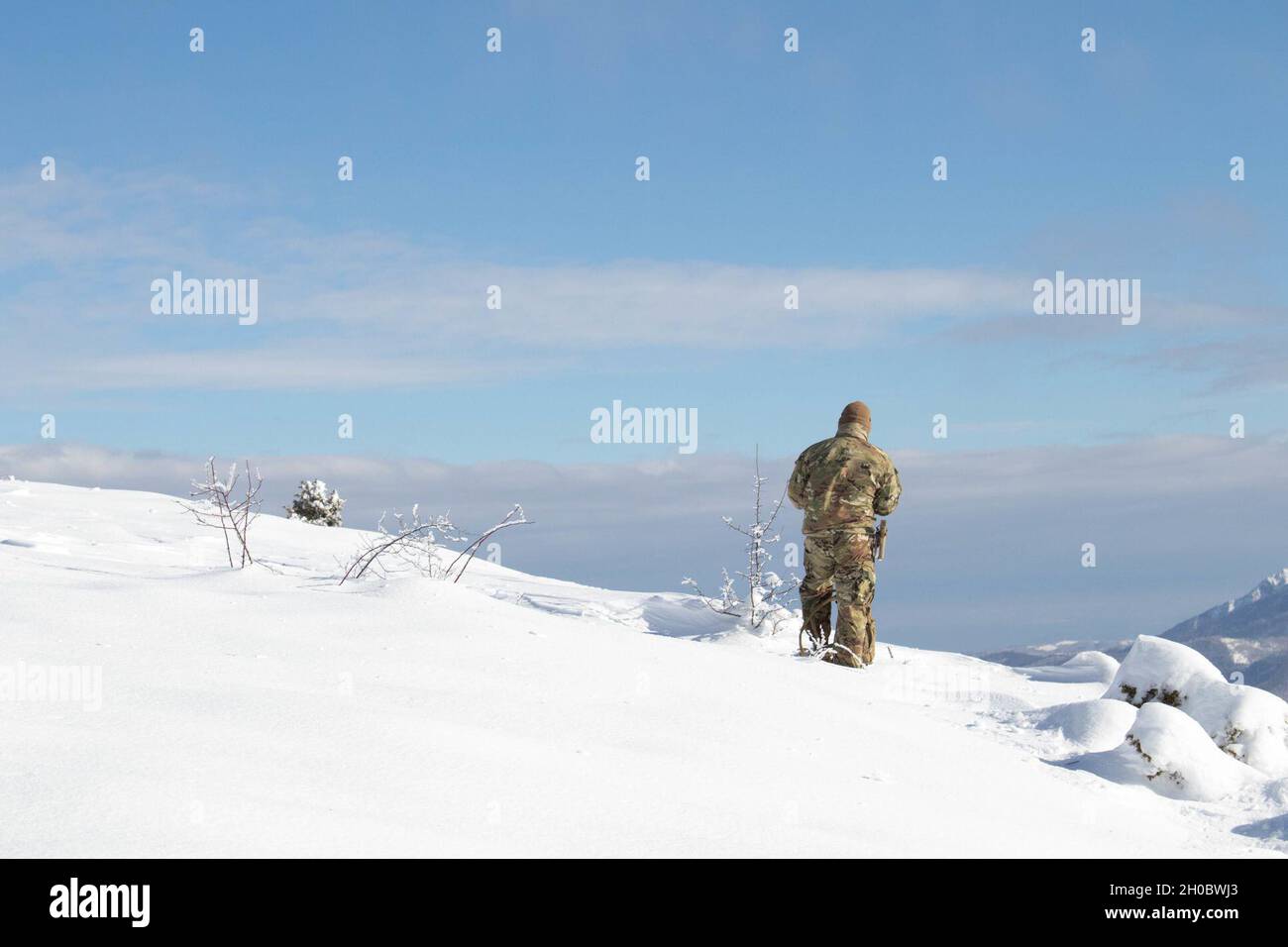 Ein Soldat der Nationalgarde der Iowa-Armee, der dem Regionalkommando Ost, der Kosovo Force, zugewiesen wurde, patrouilliert während einer HLS-Räumungsmission entlang der administrativen Grenzlinie im Kosovo am 20. Januar 2021 einen Hubschrauberlandeplatz. Regelmäßige HLS-Missionen sind für die KFOR unerlässlich, um ein sicheres Umfeld für alle Menschen im Kosovo zu gewährleisten. Der Schnee war zu tief, um den Platz gründlich zu räumen, so dass die Crew zur Basis zurückkehrte und weitere Freiräume durchführen wird, wenn sich die Bedingungen verbessern. Stockfoto