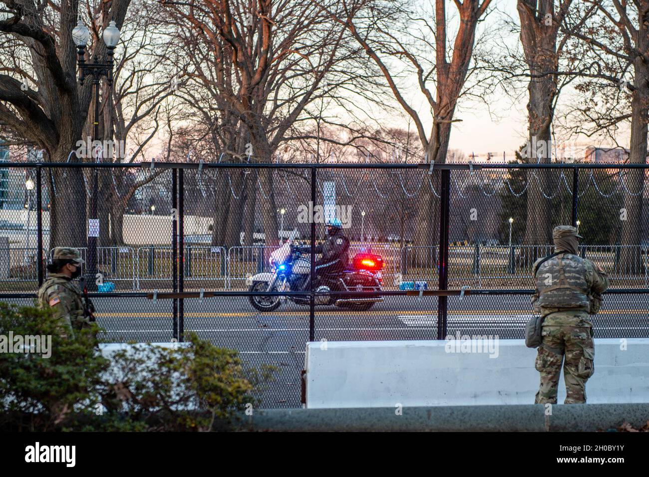 US-Soldaten mit der Oklahoma National Guard stehen Wache, während ein Polizeibeamter des US-Kapitols auf einem Motorrad in der Nähe des US-Kapitolgebäudes in Washington, D.C., am 20. Januar 2021, vorbei fährt. Mindestens 25,000 Männer und Frauen der Nationalgarde wurden autorisiert, Sicherheits-, Kommunikations- und Logistikmissionen zur Unterstützung der Bundes- und Bezirksbehörden durchzuführen, die vor und während der 59. Amtseinführung des Präsidenten geführt wurden. Stockfoto