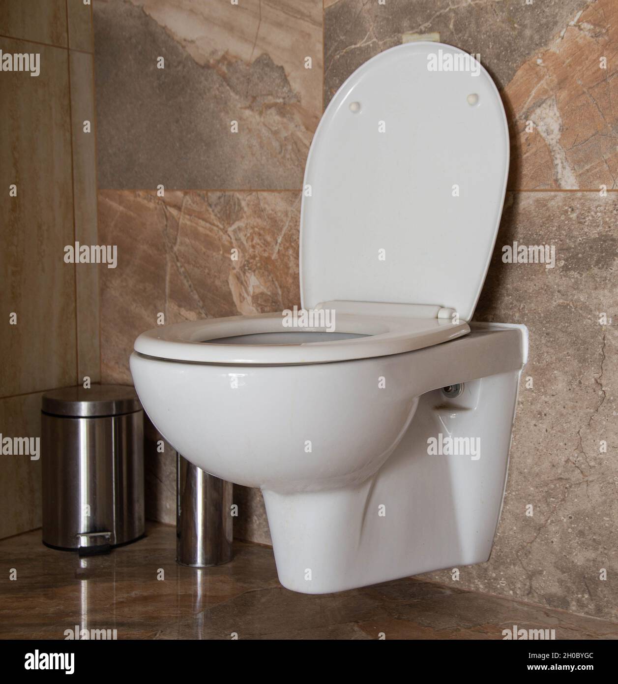 Toilette in der Toilette mit Mülleimer in der Ecke, braune Keramikfliesen.  Toilette innen Stockfotografie - Alamy