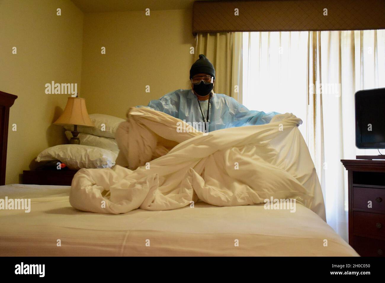 210120-N-UA321-1002 NORFOLK, VA (Jan 20, 2021) Leilani Lussier, Leiter des Housekeeping, entfernt die gesamte Bettwäsche in einem der Zimmer mit Bewegungsbeschränkung (ROM) im Anbau des Hauptquartiers. Die Zimmermädchen sind dafür verantwortlich, die Zimmer, den Gemeinschaftsbereich außerhalb der Zimmer, die Außenveranden und die Außentür gründlich zu reinigen. Stockfoto 210120-N-UA321-1002 NORFOLK, VA (Jan 20, 2021) Leilani Lussier, Leiter des Housekeeping, entfernt die gesamte Bettwäsche in einem der Zimmer mit Bewegungsbeschränkung (ROM) im Anbau des Hauptquartiers. Die Zimmermädchen sind dafür verantwortlich, die Zimmer, den Gemeinschaftsbereich außerhalb der Zimmer, die Außenveranden und die Außentür gründlich zu reinigen. Stockfoto