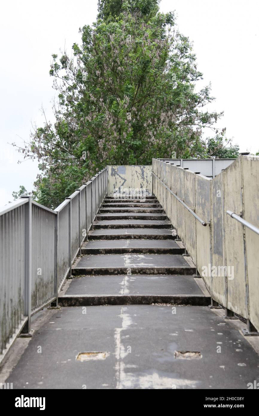 Furchterregend einschüchternd aussehende Stufen für eine Fußgängerbrücke, die über eine Eisenbahnstrecke führt, 2021 Stufen Brücke Stockfoto