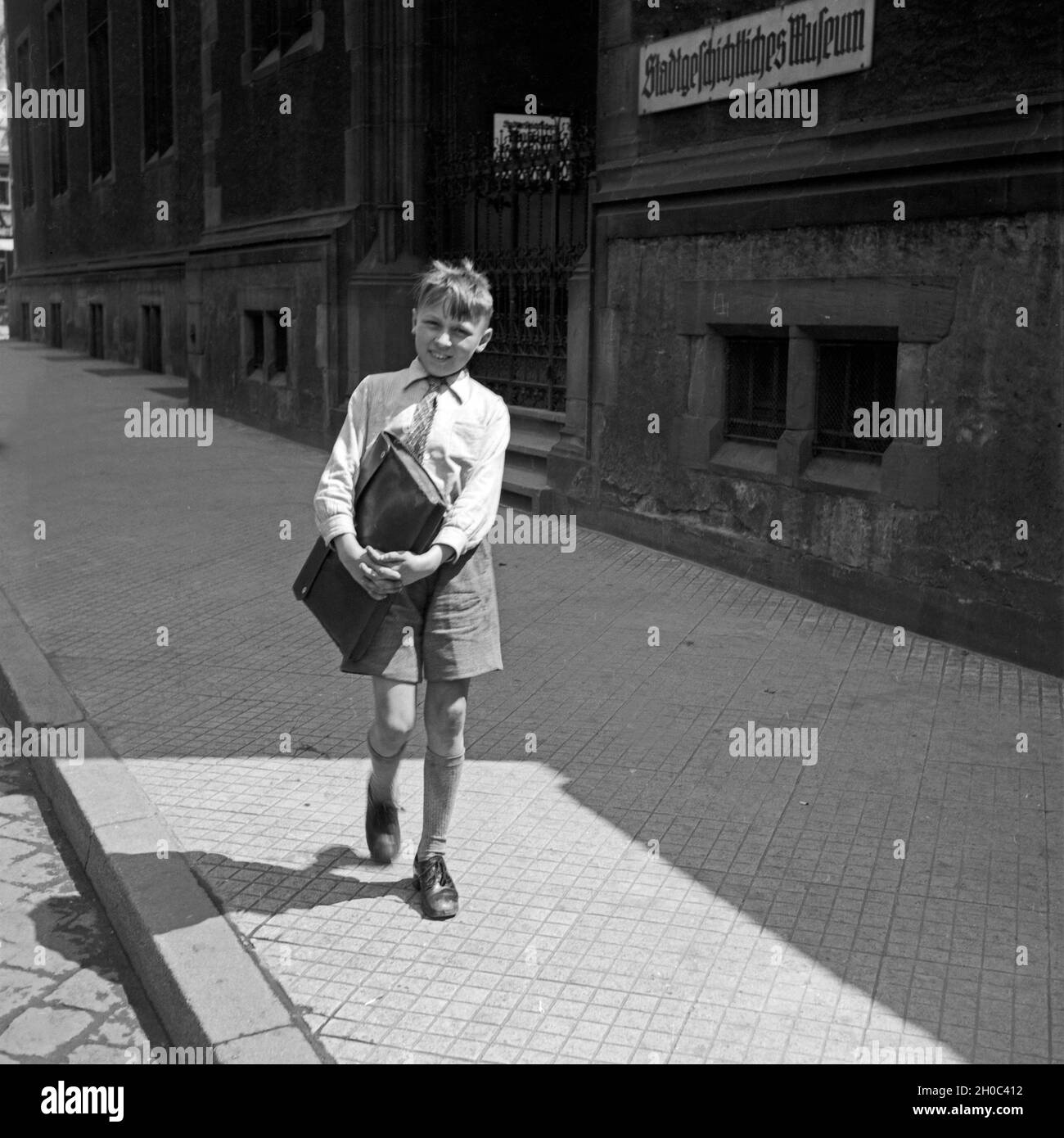 Fröhlischer Frankfurter Bub geht lachend bin Stadtgeschichtlichen Museum in Frankfurt am Main vorbei, Deutschland 1930er Jahre. Happy Boy fom Frankfurt vorbei am historischen Museum, Deutschland 1930. Stockfoto