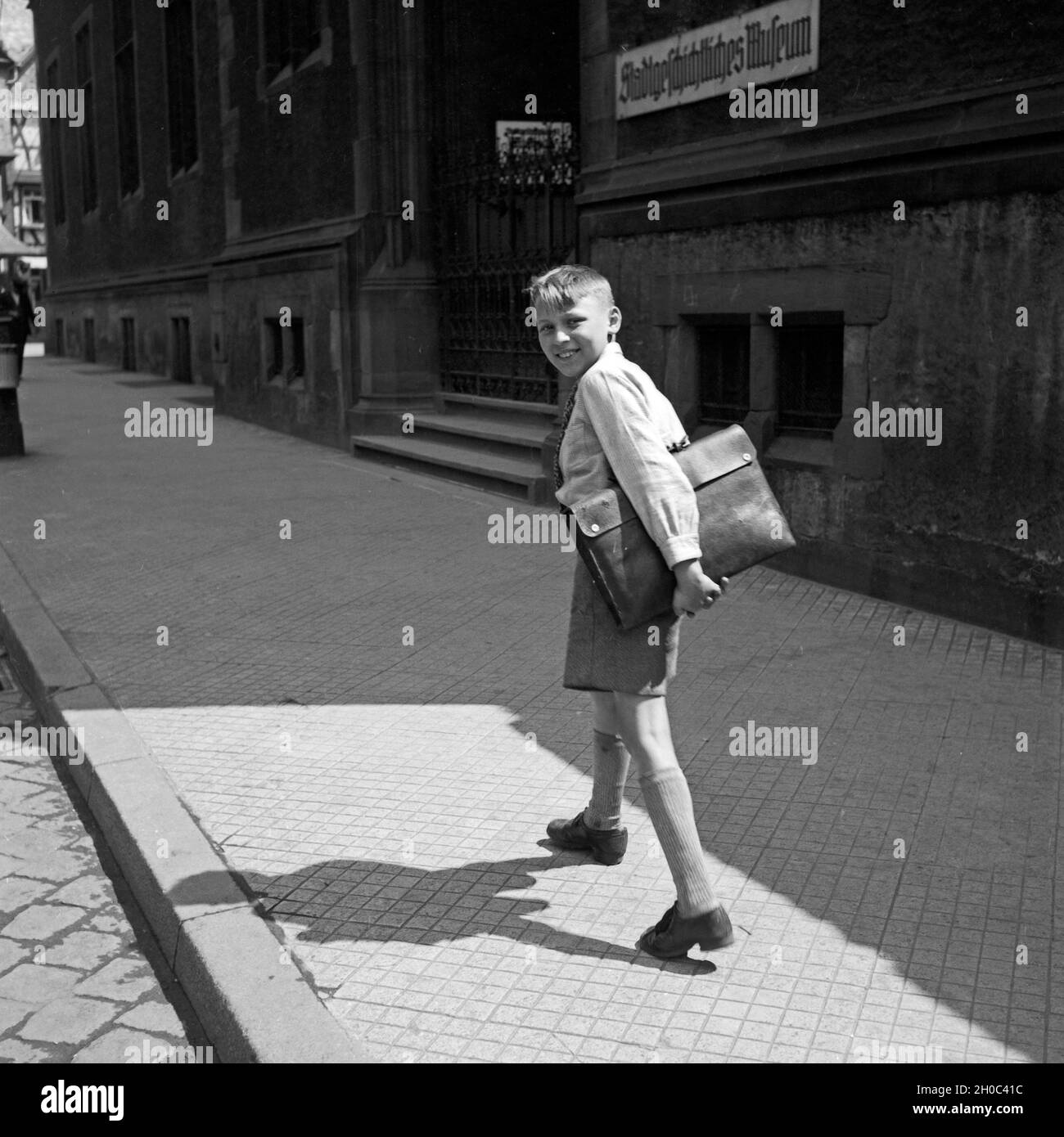 Fröhlischer Frankfurter Bub geht lachend bin Stadtgeschichtlichen Museum in Frankfurt am Main vorbei, Deutschland 1930er Jahre. Happy Boy fom Frankfurt vorbei am historischen Museum, Deutschland 1930. Stockfoto