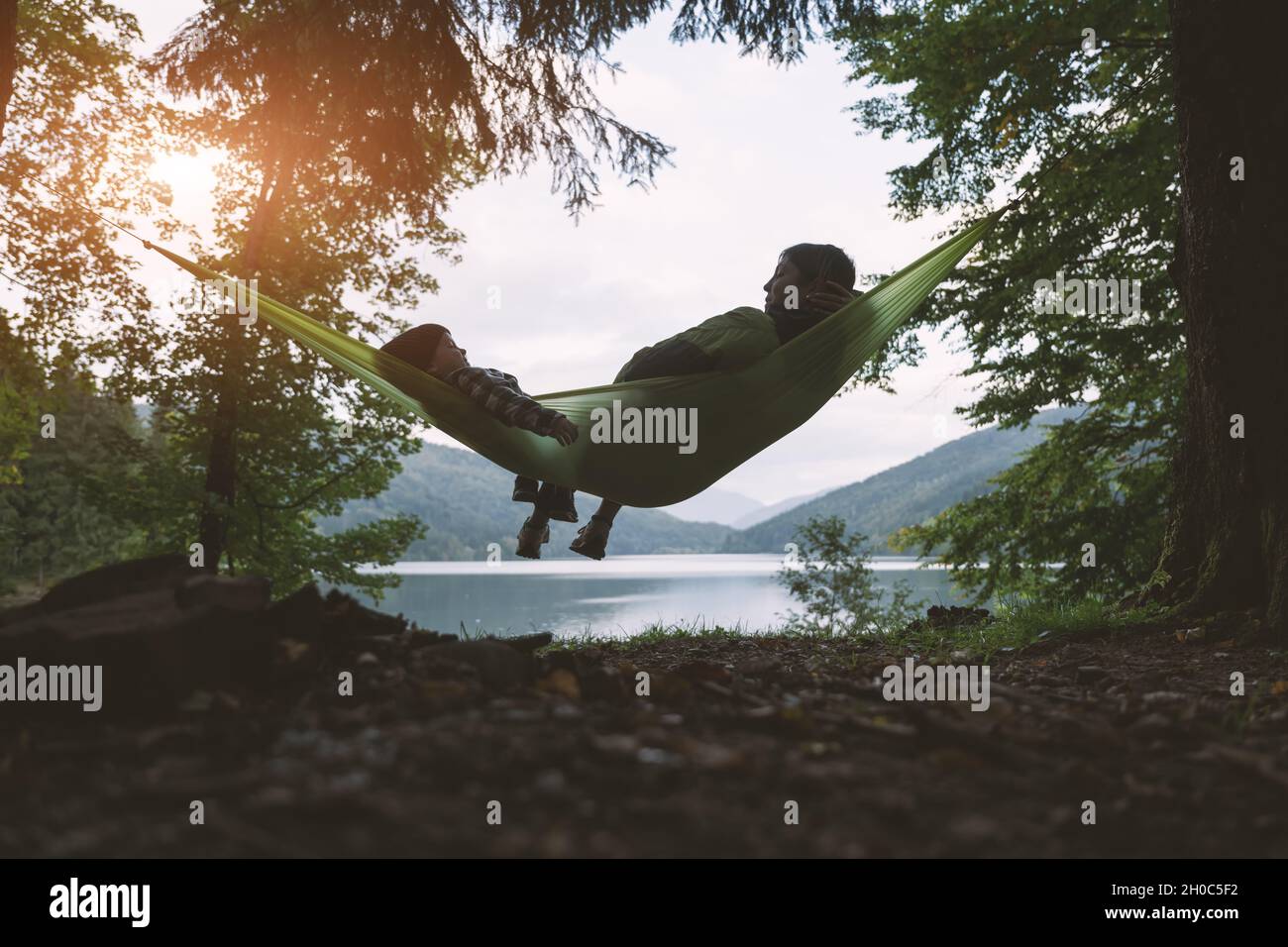 Kleines Kind mit Mutter auf Hängematte auf Waldsee Hintergrund. Kindheit mit naturliebenden Konzept Stockfoto