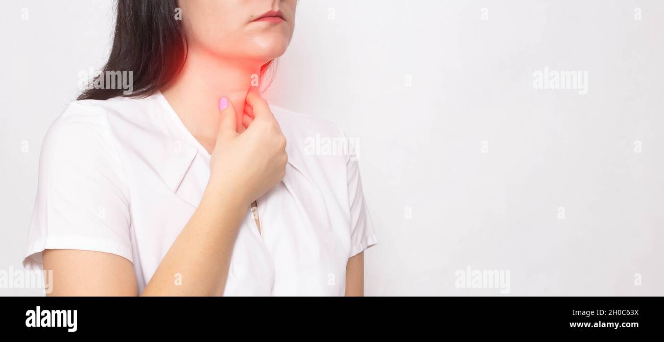 Das Mädchen hält sich auf weißem Grund an den schmerzenden roten Hals fest. Konzept von Halsschmerzen, Kehlkopfentzündung und Halsschmerzen beim Coronavirus. Platz für Text kopieren Stockfoto