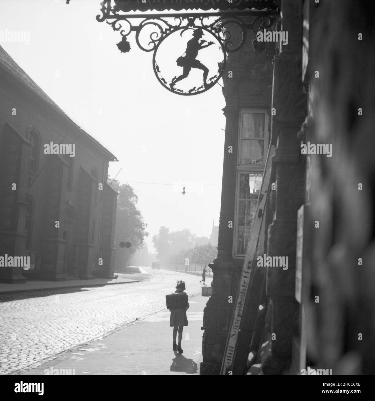 Schulkind vor einem Haus mit dem Rattenfänger in Hameln an der Weser, Deutschland 1930er Jahre. Schule Mädchen vor einem Haus mit Symbol der Rattenfänger in der Altstadt von Hameln auf der Weser, Deutschland 1930. Stockfoto