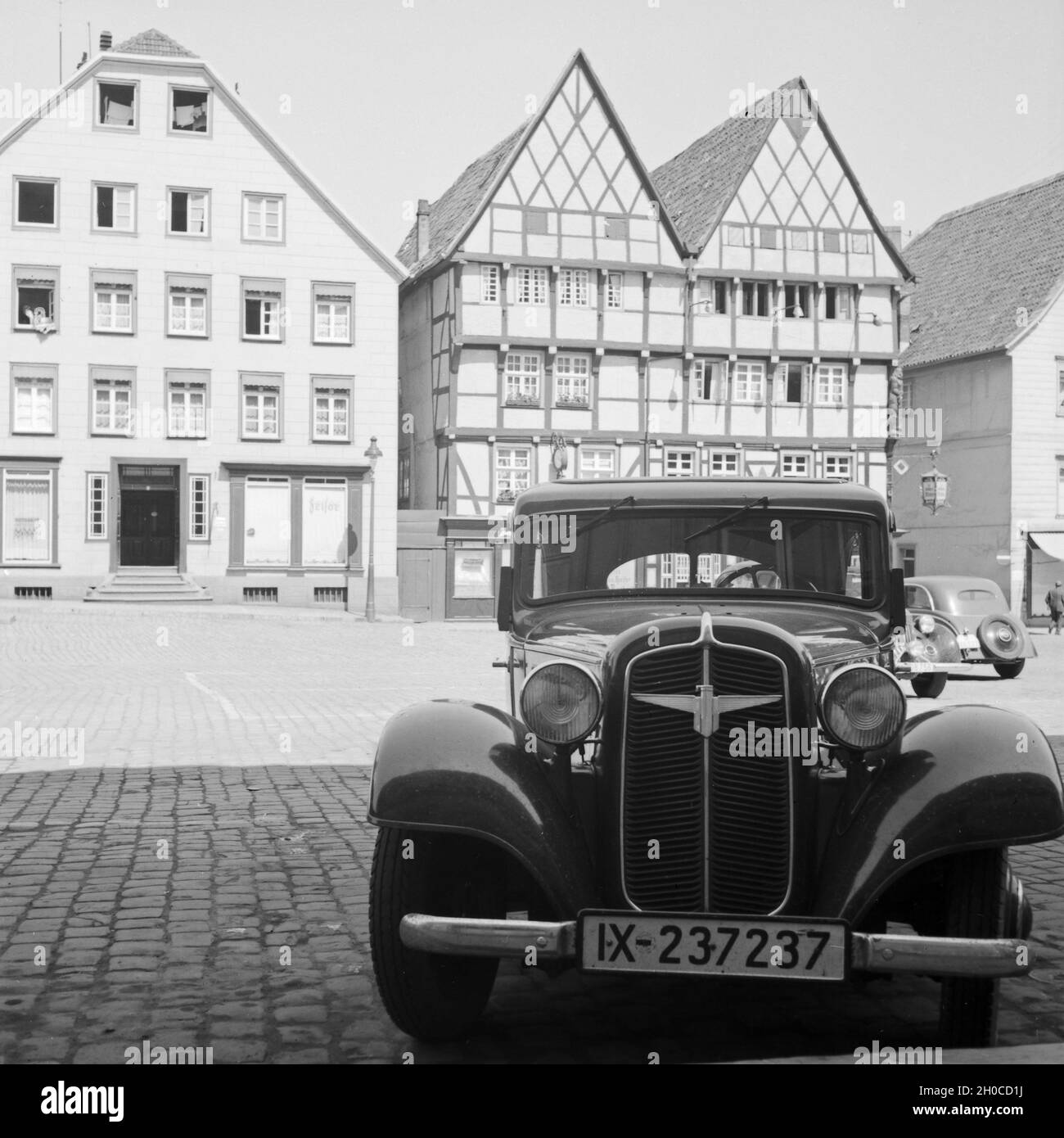 Ein Auto der Marke Adler Parkt Vor Fachwerkhäusern in der Altstadt von Soest in Westfalen, Deutschland, 1930er Jahre. Ein Auto der Marke Adler Parkplatz Fachwerkhäuser in der alten Stadt Soest in Westfalen, Deutschland der 1930er Jahre. Stockfoto