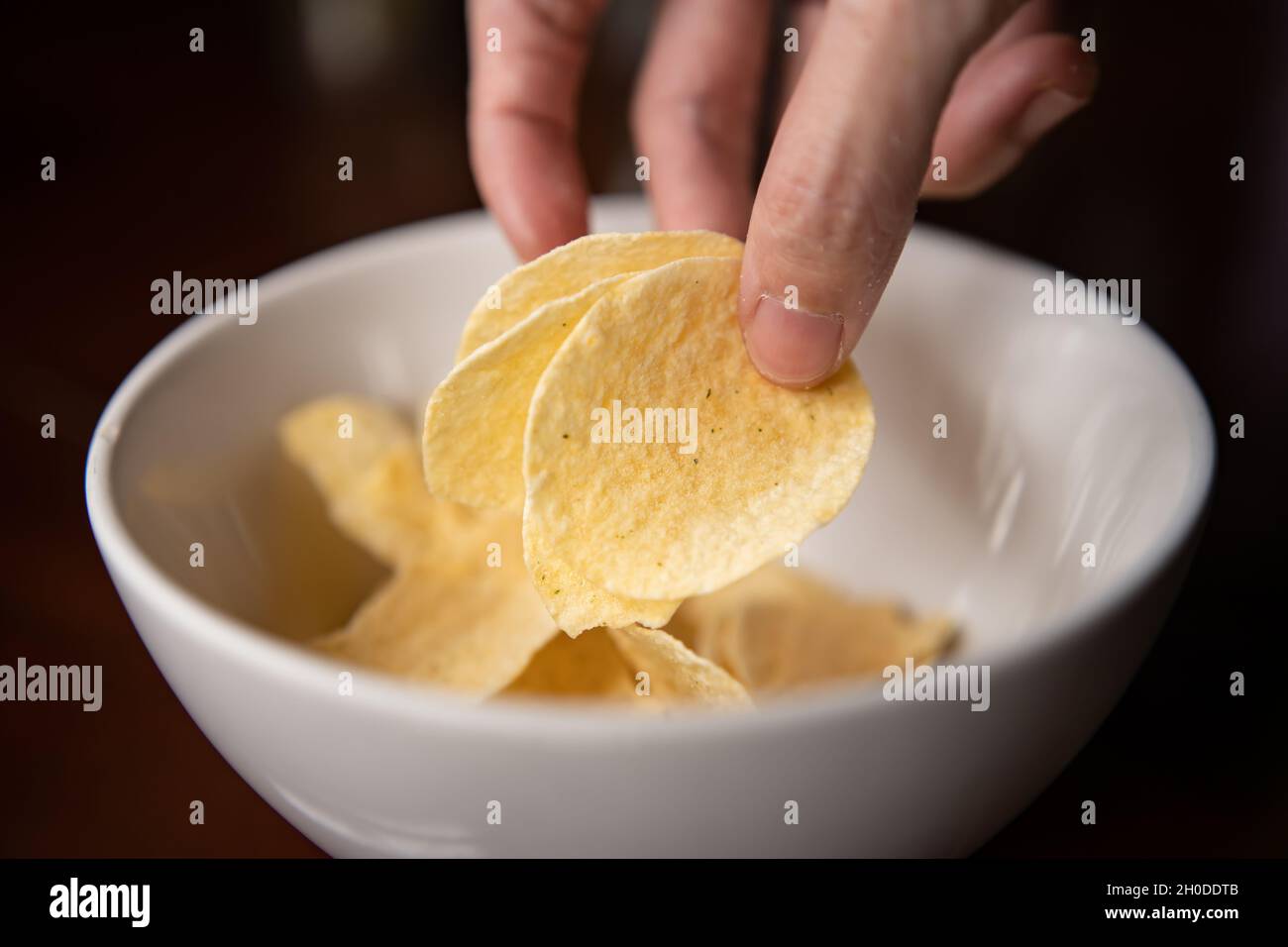 Kartoffelchips aus einer Schüssel pflücken Stockfoto