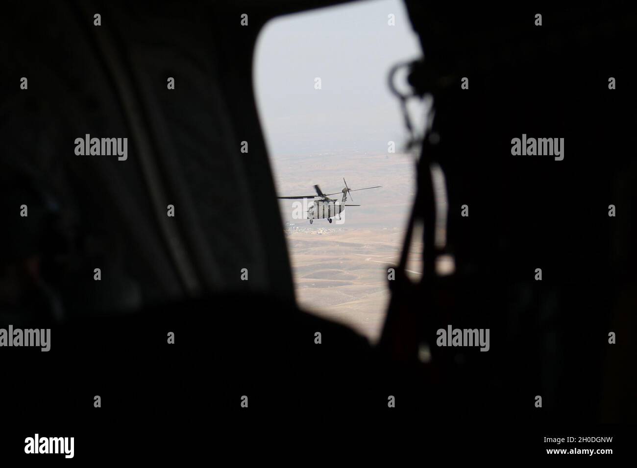 Ein Hubschrauber der Serie UH-60 Black Hawk, der von Soldaten mit dem Assault Helicopter Bataillon 1-137, der 28. Expeditionary Combat Aviation Brigade, betrieben wird, ist durch das Fenster eines CH-47 Chinook Hubschraubers sichtbar, während sie über den Irak fliegen. Stockfoto