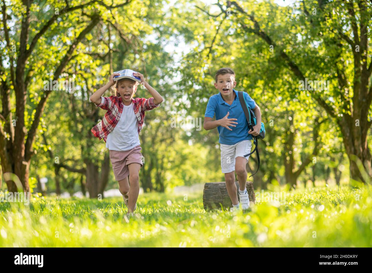 Fröhlicher Junge und Mädchen laufen im Park Stockfoto