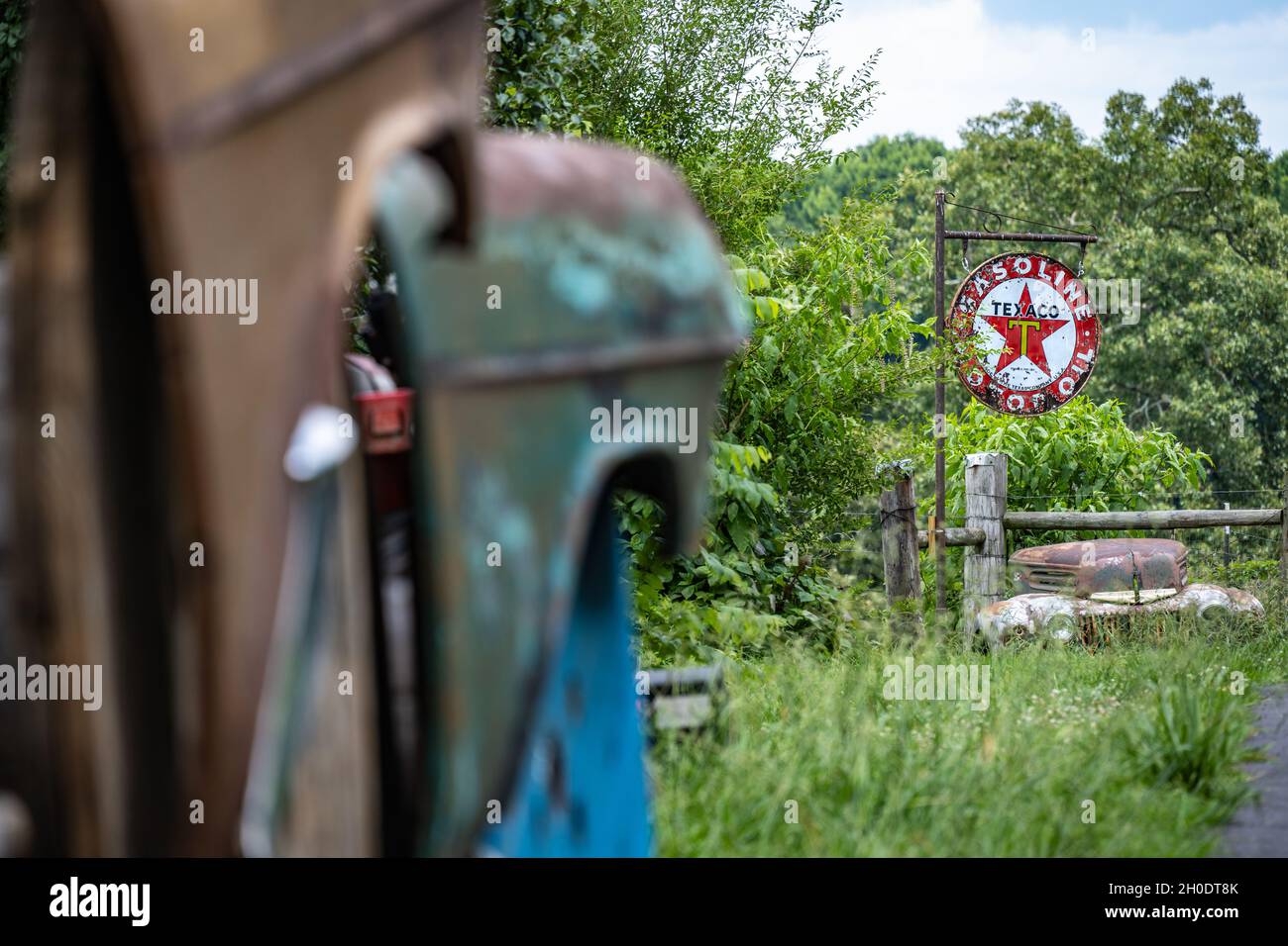 Vintage Texaco Gasoline & Motor Oil Schild mit der verwitterten Front eines klassischen Ford Fahrzeugs bei Crazy Mule Art & Antiques in Lula, Georgia. (USA) Stockfoto