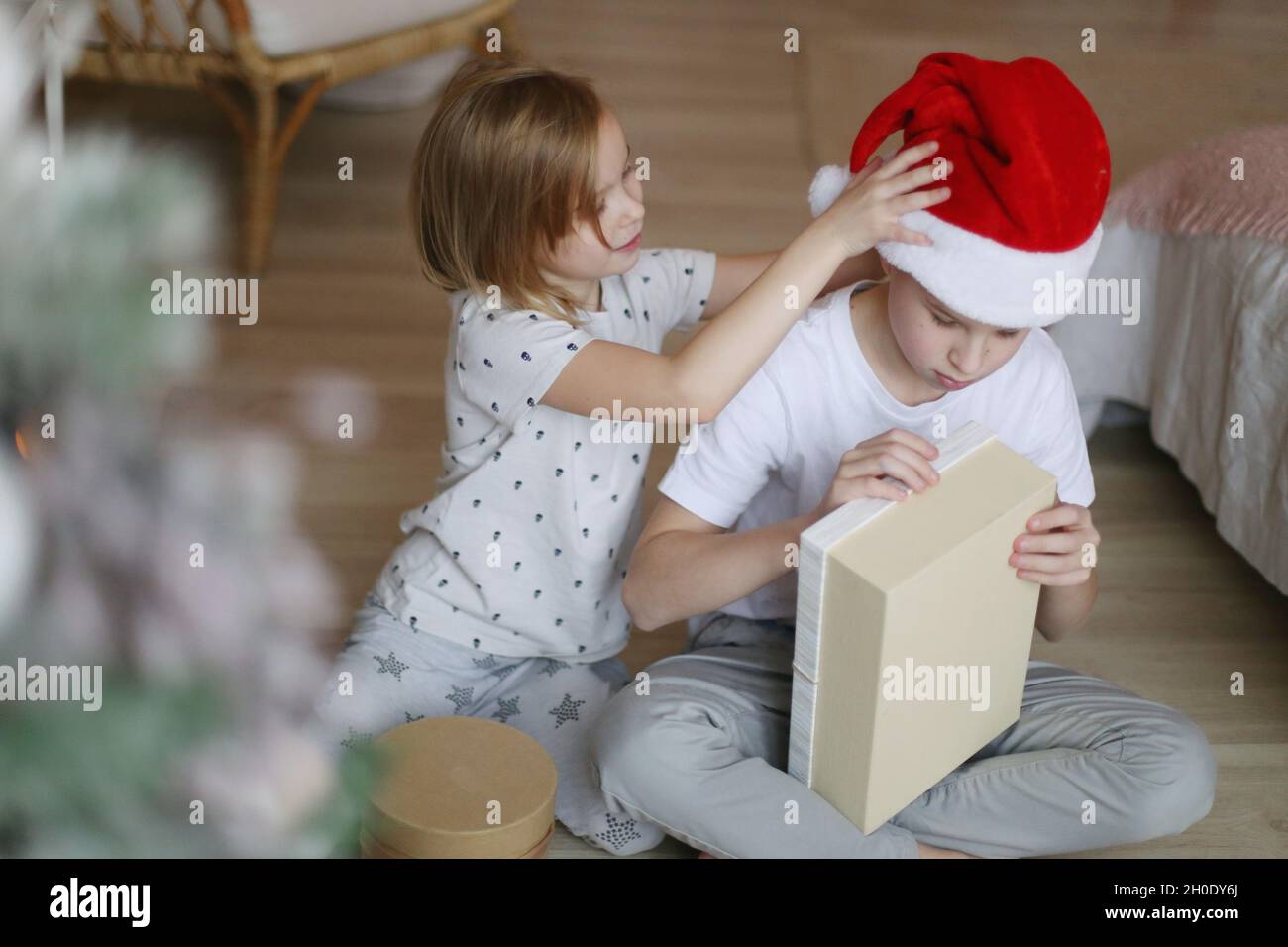 Bruder und Schwester auf dem Boden neben dem weihnachtsbaum. Stockfoto