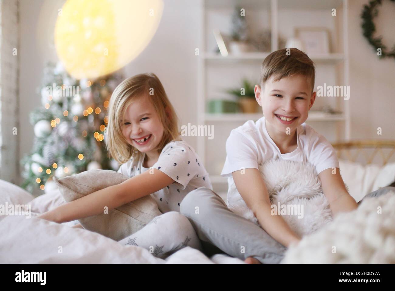 Kinder sitzen auf dem Bett und schauen lächelnd auf die Kamera. Stockfoto