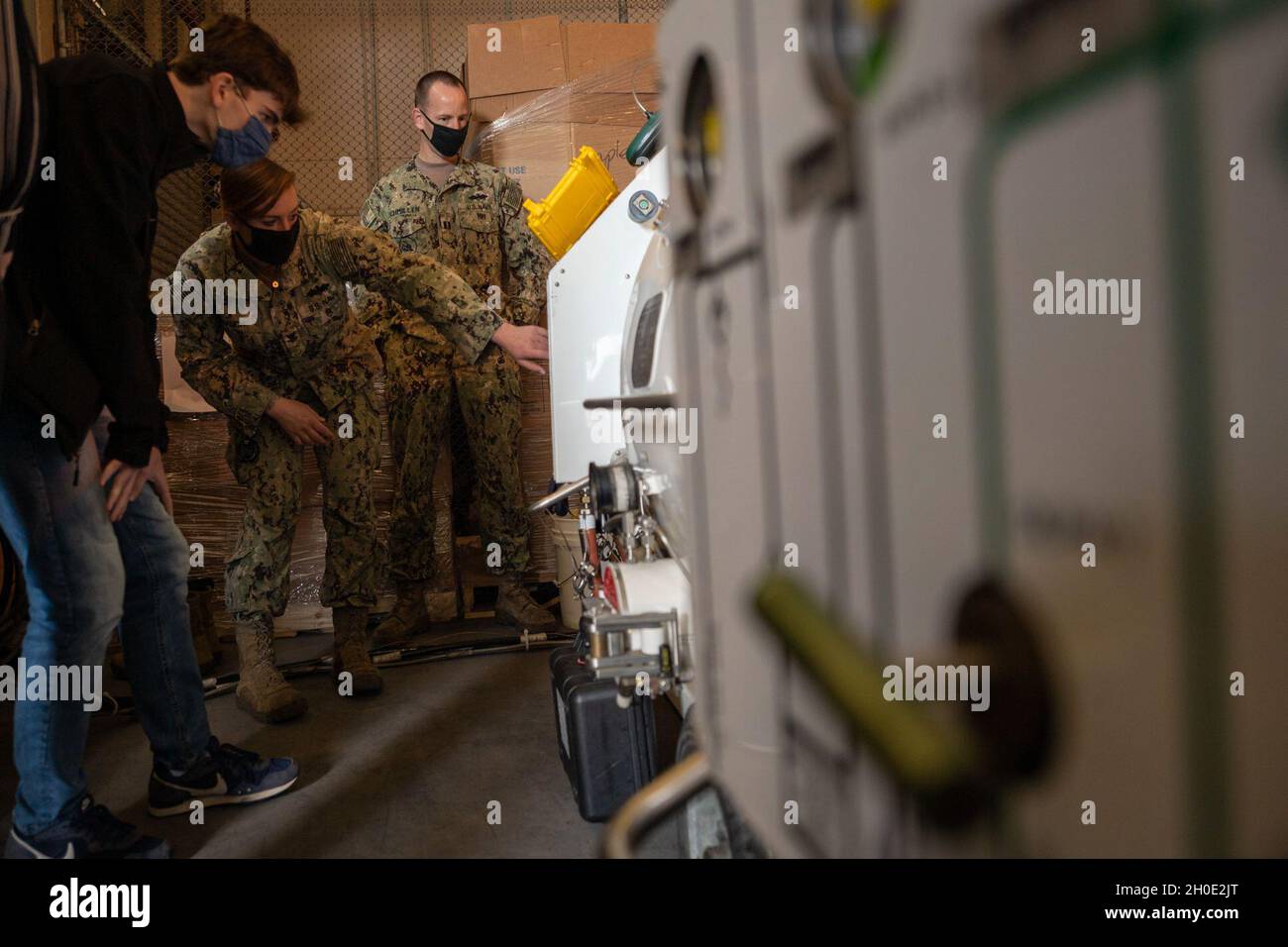 MARINESTÜTZUNGSAKTIVITÄTEN NEAPEL, Italien (5. Februar 2021) Baumechaniker der 2. Klasse Kendra Rauch, der dem Unterwasser-Konstruktionsteam 1 zugewiesen wurde, erklärt Thomas Larrivee, Student im MINT-Programm am Department of Defense Education Activity (DODEA) Neapel, Während einer Taucherdemonstration mit dem transportablen Rekompressionssystem. Die Expeditionary Engineering Business Line des Naval Facilities Engineering Systems Command (NAVFAC) Europe Africa Central organisierte diese Eröffnungsveranstaltung in Abstimmung mit Freiwilligen der U.S. Naval Forces Europe-Africa. Stockfoto