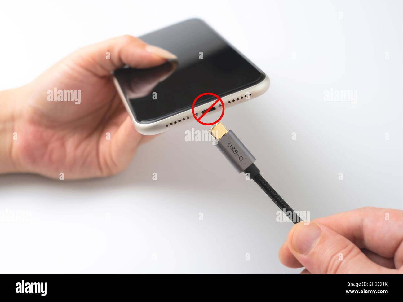 Die Europäische Union verbietet Blitzkabel. Hand versucht, Typ-c-Kabel an Smartphone anschließen. Stockfoto