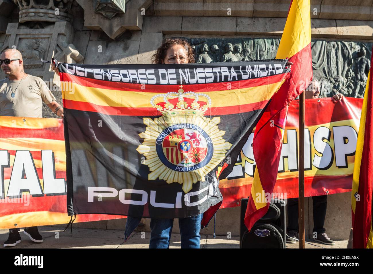 Eine Frau, die mit einer Flagge des Nationalen Polizeikorps neben der Blumengabe auf der Statue von Christoph Kolumbus in Barcelona gesehen wurde.Menschen haben an der Blumengabe an die Statue von Christoph Kolumbus in Barcelona anlässlich des Hispanic Day, der von der rechtsextremen Partei VOX organisiert wurde, am 12. Oktober teilgenommen. Es gab den VOX-Sprecher im katalanischen Parlament, Ignacio Garriga, begleitet von den beiden Sprechern der katalanischen Kammer, Juan Garriga und Antonio Gallego, sowie dem Abgeordneten Andres Bello. (Foto von Thiago Prudencio/SOPA Images/Sipa USA) Stockfoto