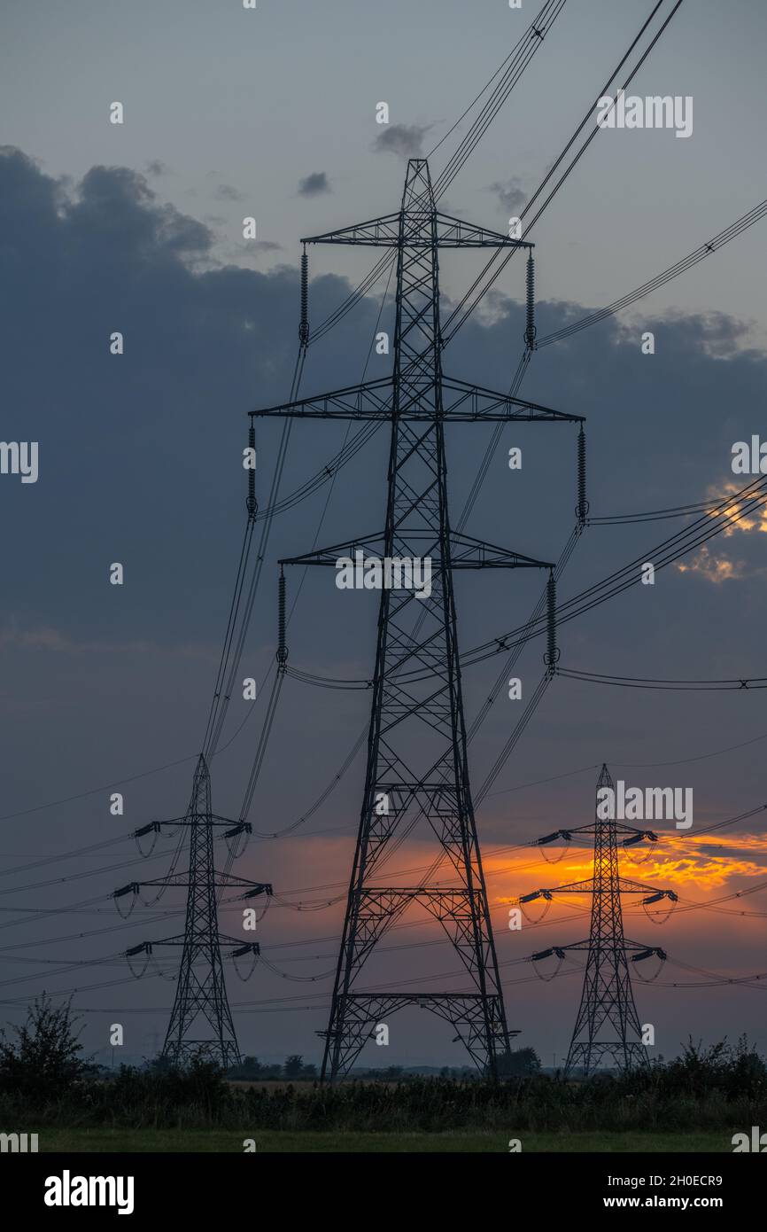 Masten und Stromleitungen bei Sonnenuntergang auf den Sümpfen von Higham Kent. Stockfoto