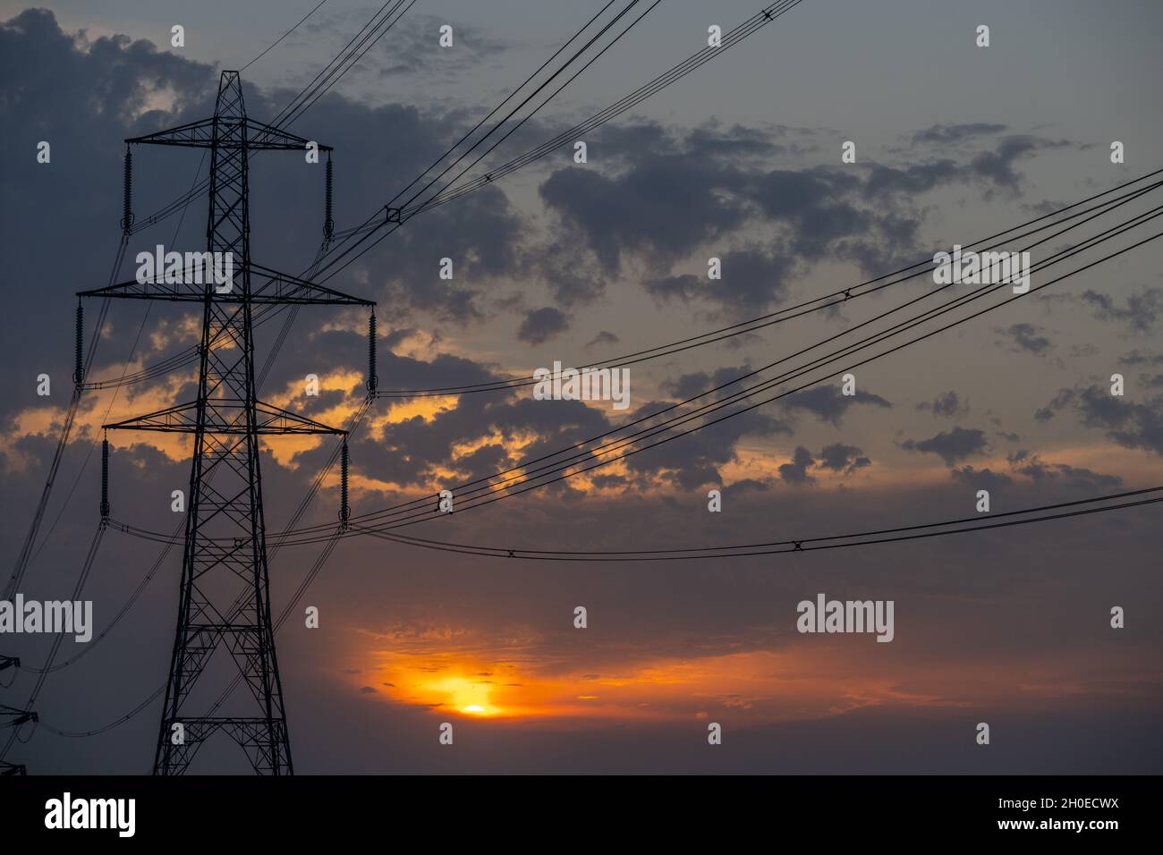 Masten und Stromleitungen bei Sonnenuntergang auf den Sümpfen von Higham Kent. Stockfoto