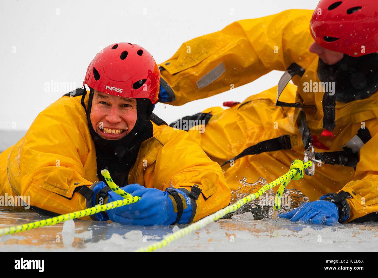 Ein Feuerwehrmann mit der 788. Civil Engineer Squadron Fire Department auf der Wright-Patterson Air Force Base, Ohio, hilft einem „Opfer“, als er am 10. Februar 2021 während des Eisrettungstrainings aus dem eisigen Wasser von Bass Lake gezogen wird. Das Eis am Basissee frierte 4 Zoll tief ein, was der Abteilung die Möglichkeit gab, sicher für die Herausforderungen zu trainieren, Menschen zu retten, die durch die Oberfläche gefallen sind. Stockfoto