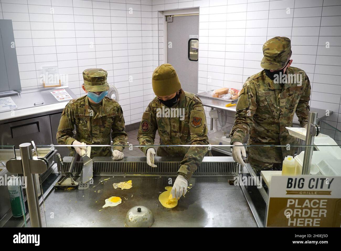 Chief Master Sgt. Der Luftwaffe Joanne S. Bass, Mitte, arbeitet zwischen Senior Airman Elizabeth Goldsmith, links, 319th Force Support Squadron Food Service Geselle, Und Airman 1. Klasse Samuel Hood, 319 FSS-Lehrling, um ein Omelett in der Speiseeinrichtung auf der Grand Forks Air Force Base, N.D., 12. Februar 2021 zu machen. Bass besuchte Grand Forks während seiner kältesten Woche noch in diesem Winter; Umgebungstemperaturen unter minus 20, aber das hielt sie oder ihr Team nicht davon ab, verschiedene Arbeitsplätze zu besuchen, um sich mit Flugleuten zu treffen. Stockfoto