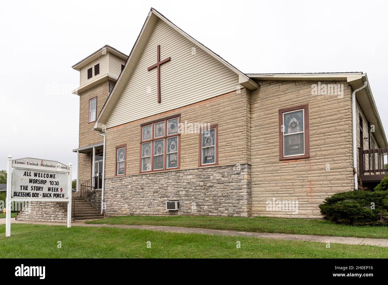 Die Lyons United Methodist Church aus beigefarbenem Stein, mit Glockenturm und Buntglasfenstern, in Lyons, Greene County, Indiana, Mittelwestamerika. Stockfoto