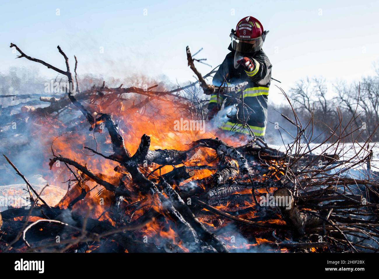 Master-Sgt. James Betts, Leiter des Assistenten zur Brandverhütung bei der Zivilingenieur-Staffel, fügt einem kontrollierten Brand am 8. Februar 2021 auf der McConnell Air Force Base, Kansas, Holz hinzu, das mit Rindenkäfer infiziert ist. Um sicherzustellen, dass das Holz sicher und rechtzeitig verbrannt wurde, wurde das Holz gekonnt gestapelt, sodass das Feuer schneller und heißer brannte. Stockfoto