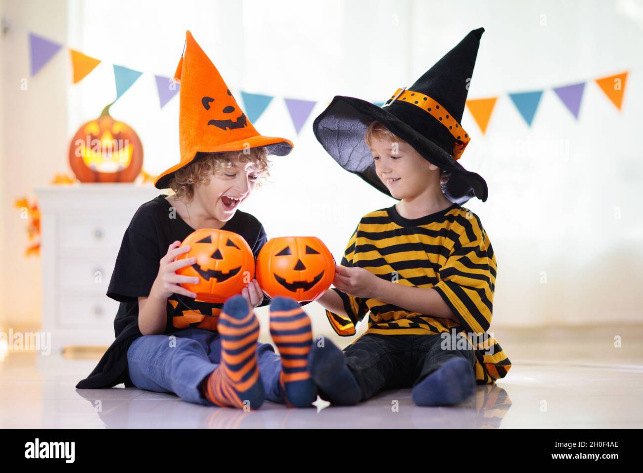 Kleines Mädchen und Junge im Hexenkostüm auf Halloween Trick or Treat. Kinder halten Süßigkeiten in Kürbis Laterne Eimer. Kinder feiern Halloween Stockfoto