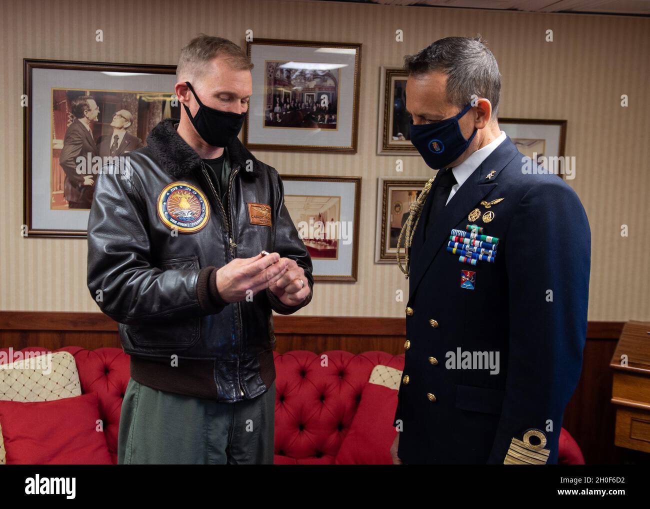 US Navy Capt. Cassidy Norman, Kommandant des Flugzeugträgers USS John C. Stennis (CVN 74), links, präsentiert dem Marinechelakttaché, Capt. Gianfranco Vizzini, eine Challenge-Münze im Rahmen eines Geschenkwechsels in der Kabine des Kapitäns an Bord der John C. Stennis in Norfolk, Virginia, Februar 22, 2021. John C. Stennis arbeitet mit Newport News Shipbuilding zusammen, um die Überholung des Tankkomplexes planmäßig mit einer geschulten, widerstandsfähigen und geschlossenen Crew abzuschließen. Stockfoto