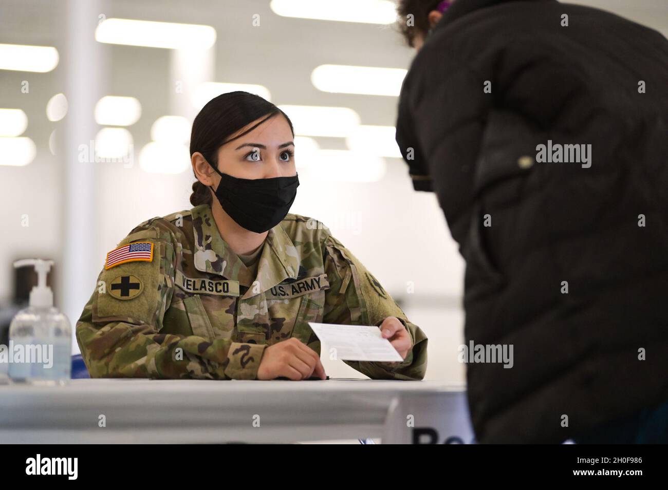 Der Spezialist der US-Armee, Brenda Velasco, Golf 634th Company, unterstützt einen Patienten in einem Gebäude, das zur Verabreichung des COVID-19-Impfstoffs in Rockford, Illinois, verwendet wurde, 23. Februar 2021. Zu ihren Aufgaben gehören Mitglieder der Nationalgarde von Illinois, die Patienten durch den Impfprozess leiten. Stockfoto