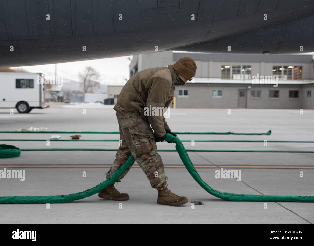 Personal Sgt. Dalen Johnson, 151st Repair and Reclamation Shop, legt während des jährlichen Absturztrainings für beschädigte oder behinderte Flugzeuge am 23. Februar 2021 auf der Roland R. Wright Air National Guard Base in Salt Lake City, Utah, Wiederherstellungskabel unter einem KC-135R aus. Die Schulung basiert auf der Zusammenkunft verschiedener Wartungsbetriebe für den Fall, dass ein Flugzeug behindert wird oder aus kargen Bedingungen entfernt werden muss. Stockfoto