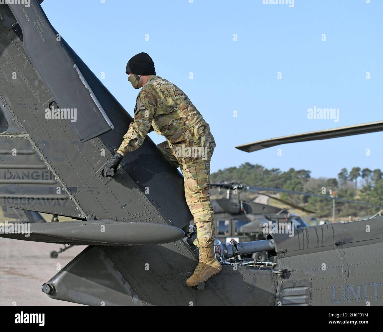 Chief Warrant Officer 3 Ryan S. Vredenburg mit Charlie Company, 1. Bataillon, 214. Aviation Regiment, 12. Combat Aviation Brigade, „Wings of Victory“, klettert den Heckboom einer UH-60A hinauf, um den Heckrotor zu inspizieren, bevor er die aeromedizinische Evakuierungsabdeckung übernimmt, Baumholder Manöver Training Area, Deutschland 24. Februar 2021. Stockfoto