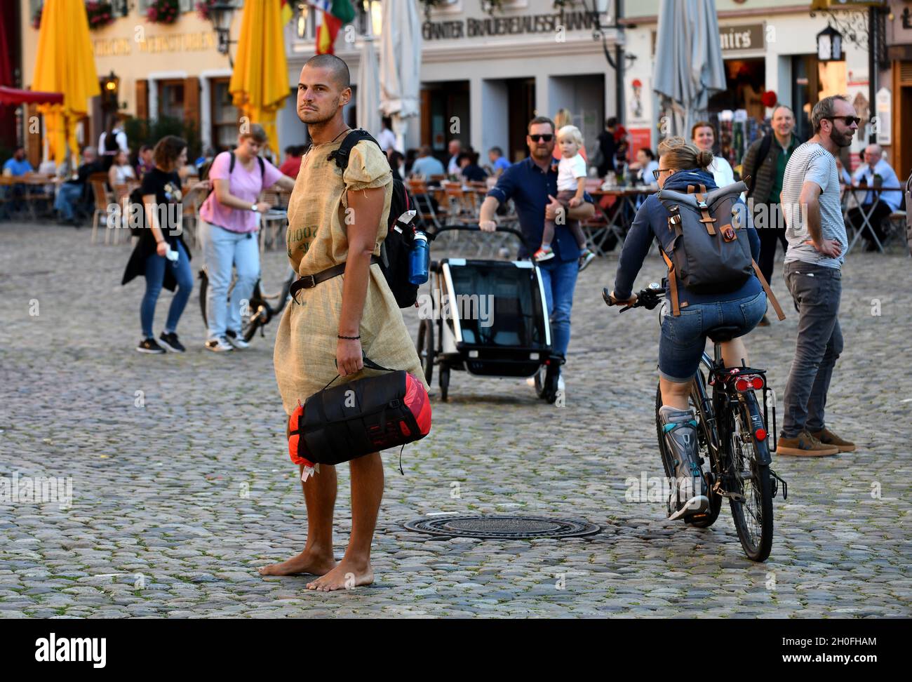 Mann in Sacktuch-Kleidung auf Kopfsteinpflaster Straße in Freiburg Deutschland. Extravagant, stylisch, Stockfoto