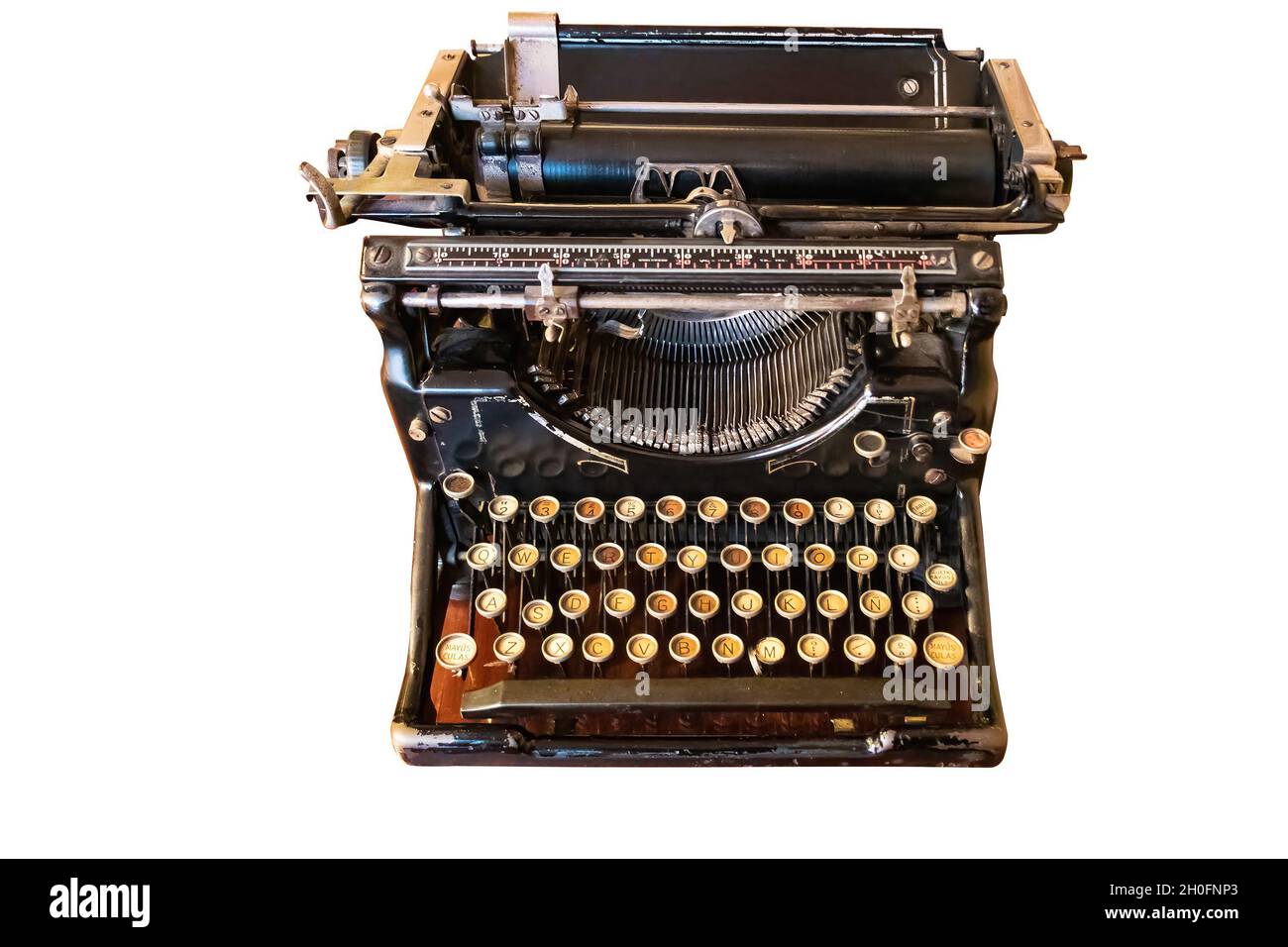 Eine alte Vintage-Schreibmaschine mit spanischer Tastatur über einem Holzschreibtisch, isoliert auf weißem Hintergrund Stockfoto