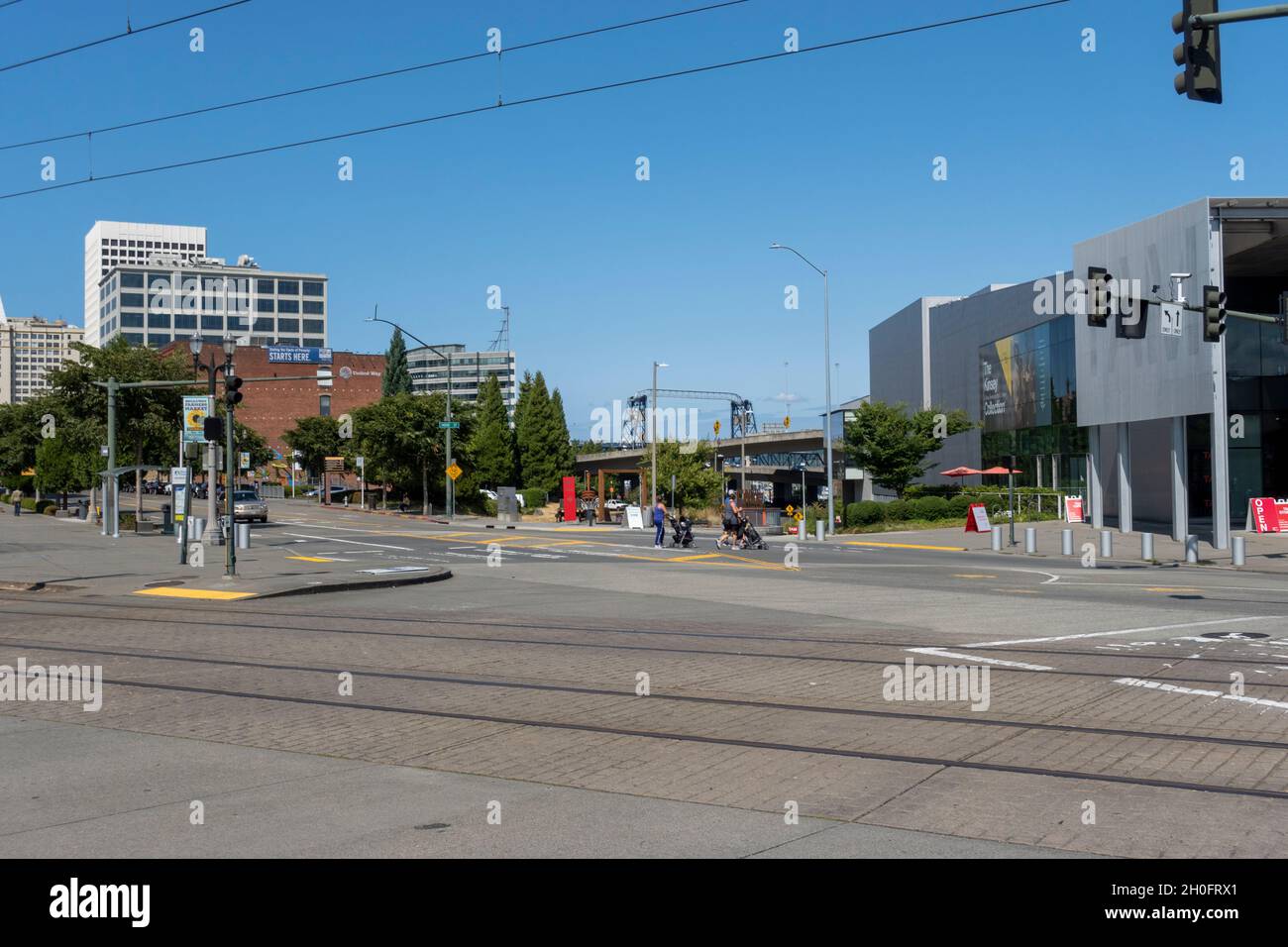 Tacoma, WA USA - ca. August 2021: Blick auf Menschen, die mit Kinderwagen auf einem Fußgängerüberweg in der Innenstadt von Tacoma in der Nähe des Kunstmuseum kreuzen. Stockfoto