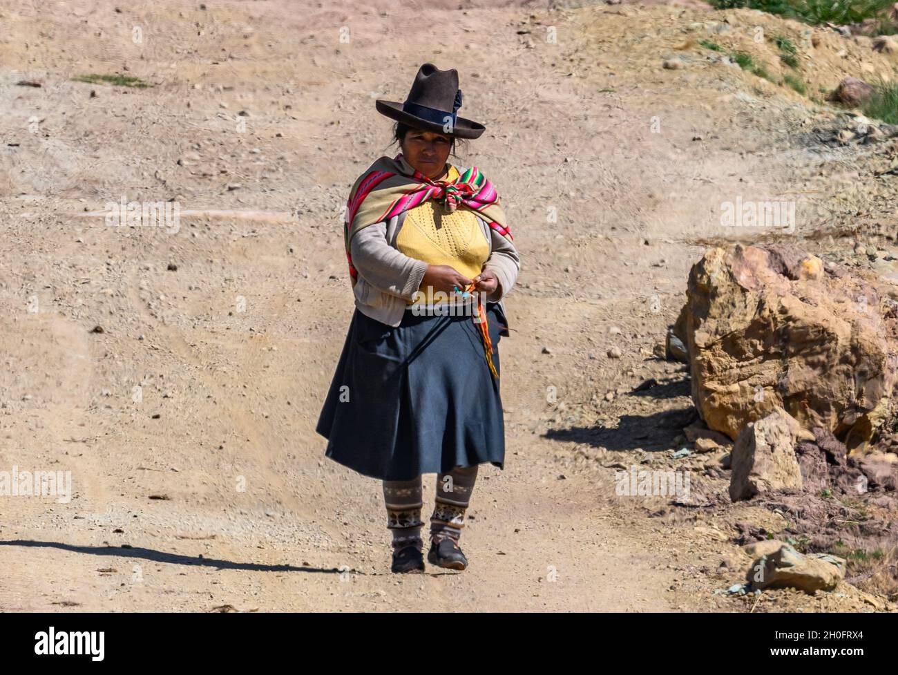 Eine gebürtige Peruanerin strickt beim Gehen auf einer unbefestigten Straße. Peru, Südamerika. Stockfoto