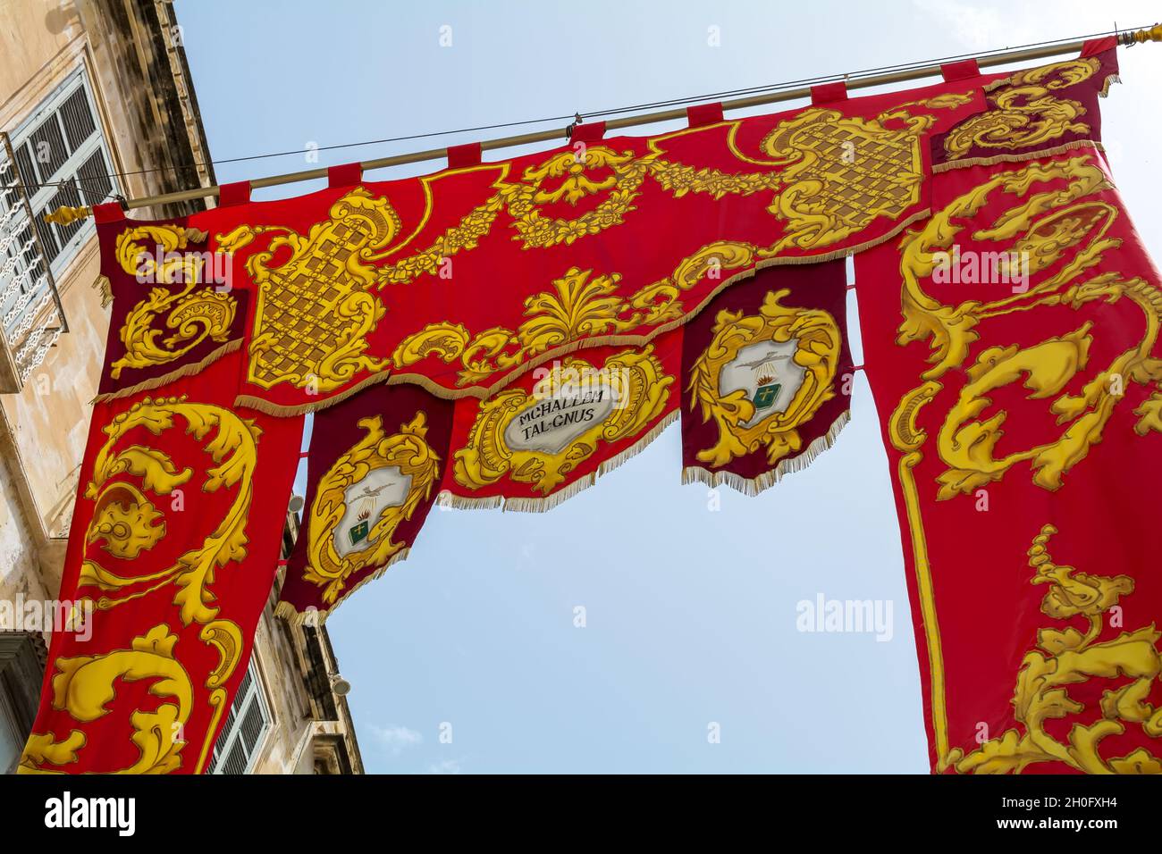 Rotes, religiös verzierte Banner als Dekoration für das Dorffest (Festa) der Muttergottes vom Mt. Carmel. Stockfoto
