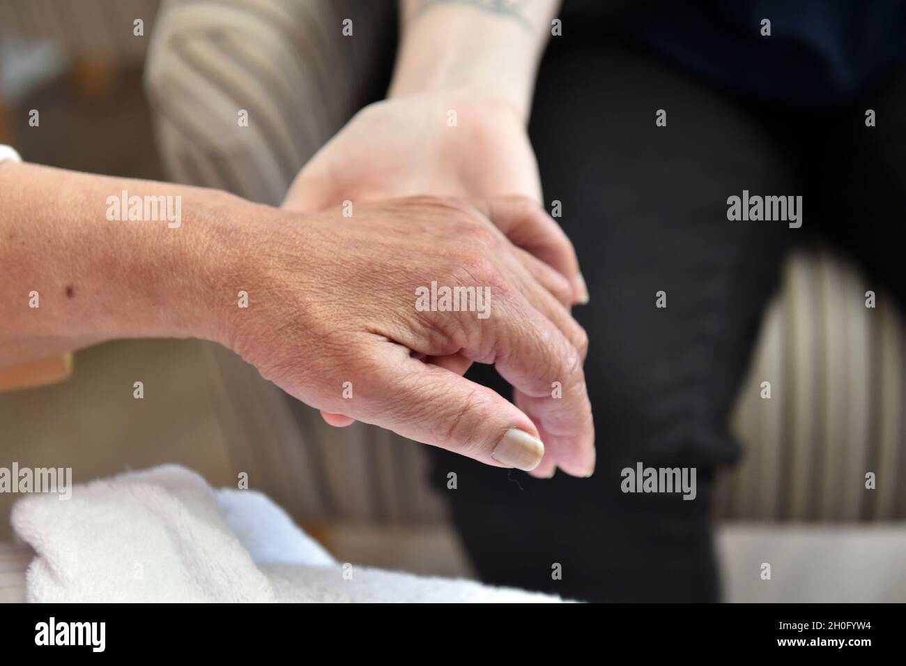 Nahaufnahme der Hände von Bewohnern in einem Pfleheim mit einem Mitarbeiter in Großbritannien Stockfoto