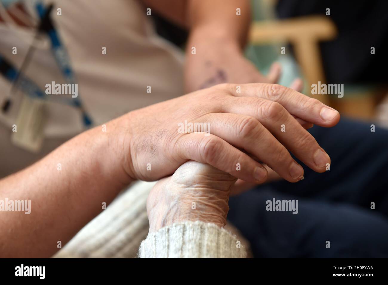 Nahaufnahme der Hände von Bewohnern in einem Pfleheim mit einem Mitarbeiter in Großbritannien Stockfoto