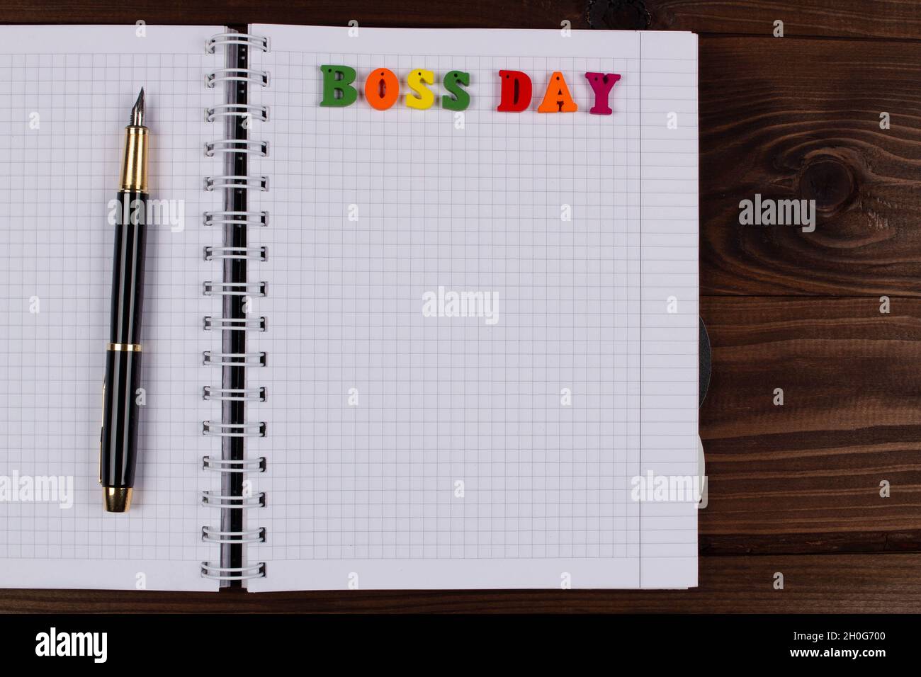 National Happy Boss Day. Bunte Buchstaben in einem karierten Übungsbuch mit Stift auf dem Tisch. Boss's Day Office Grußkarte mit Kopie Spa Stockfoto