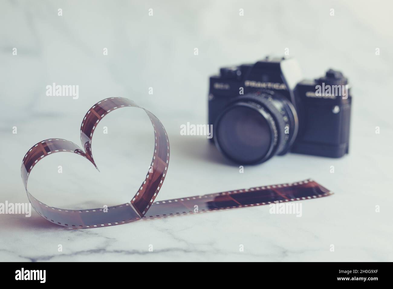 Filmnegativ in Form eines Herzens mit Vintage-Filmkamera Stockfoto