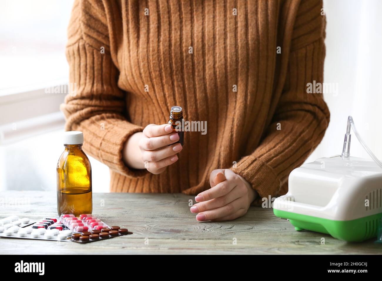 Frau mit einer Flasche ätherisches Öl und Vernebler auf dem Tisch Stockfoto