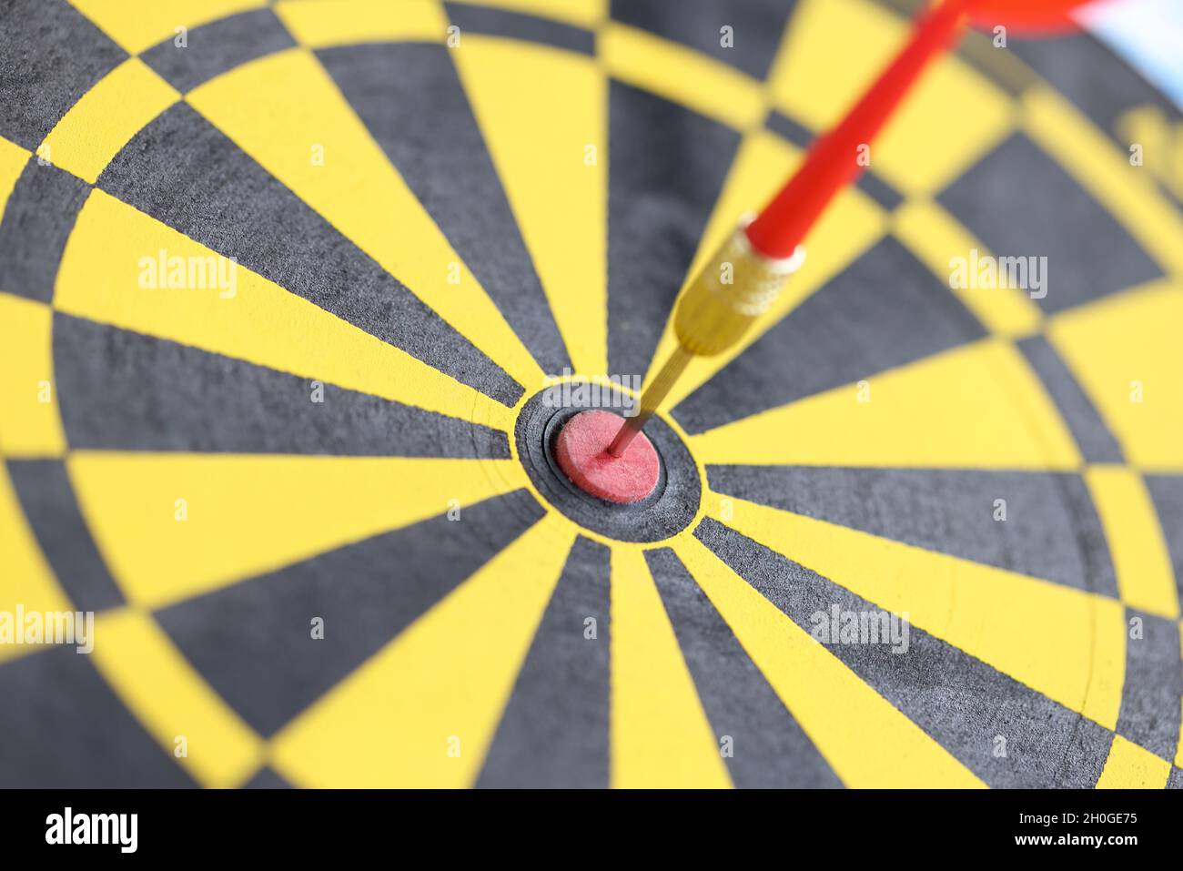 Pfeil in der Mitte der gelb-schwarzen Dartscheibe Nahaufnahme Stockfoto