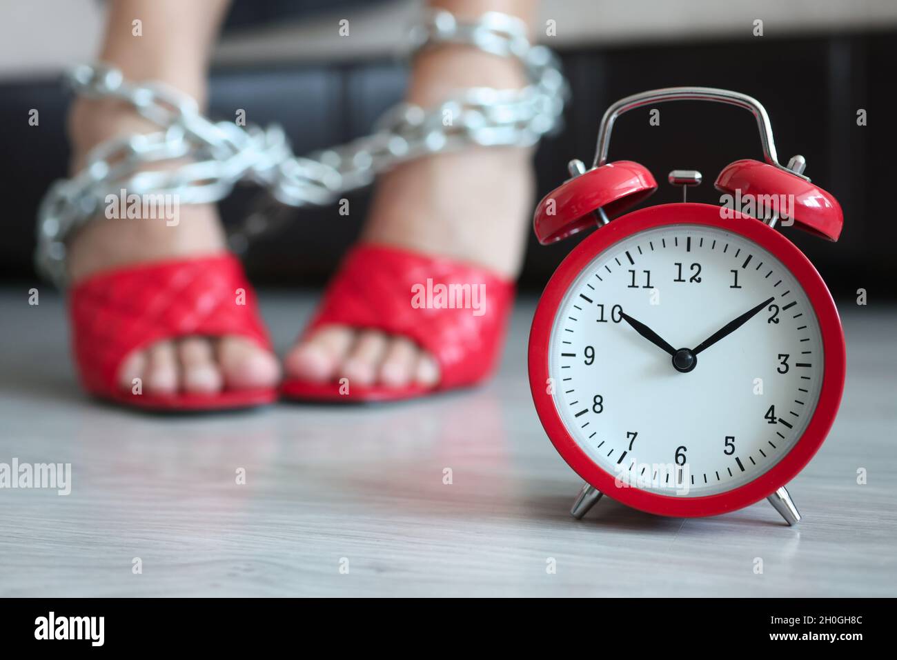 Roter Wecker um zehn Uhr morgens im Hintergrund weibliche Beine mit Kette  gebunden Stockfotografie - Alamy