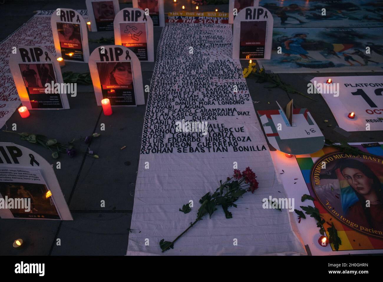 Trafalgar Square, London, England, Großbritannien 12. Oktober 2021 Columbus muss fallen! Neokolonialismus Muss Fallen! Indigene Völker protestieren gegen die Feier von Kolumbus. Symbolische Grabsteine mit den Namen und Bildern der Verstorbenen wurden auf dem Boden vor der Nationalgalerie aufgestellt, geschmückt mit Blumen und Kerzen. Im Anschluss an die Reden gab es eine Aufführung von Tänzern in indigenen Kostümen. Stockfoto