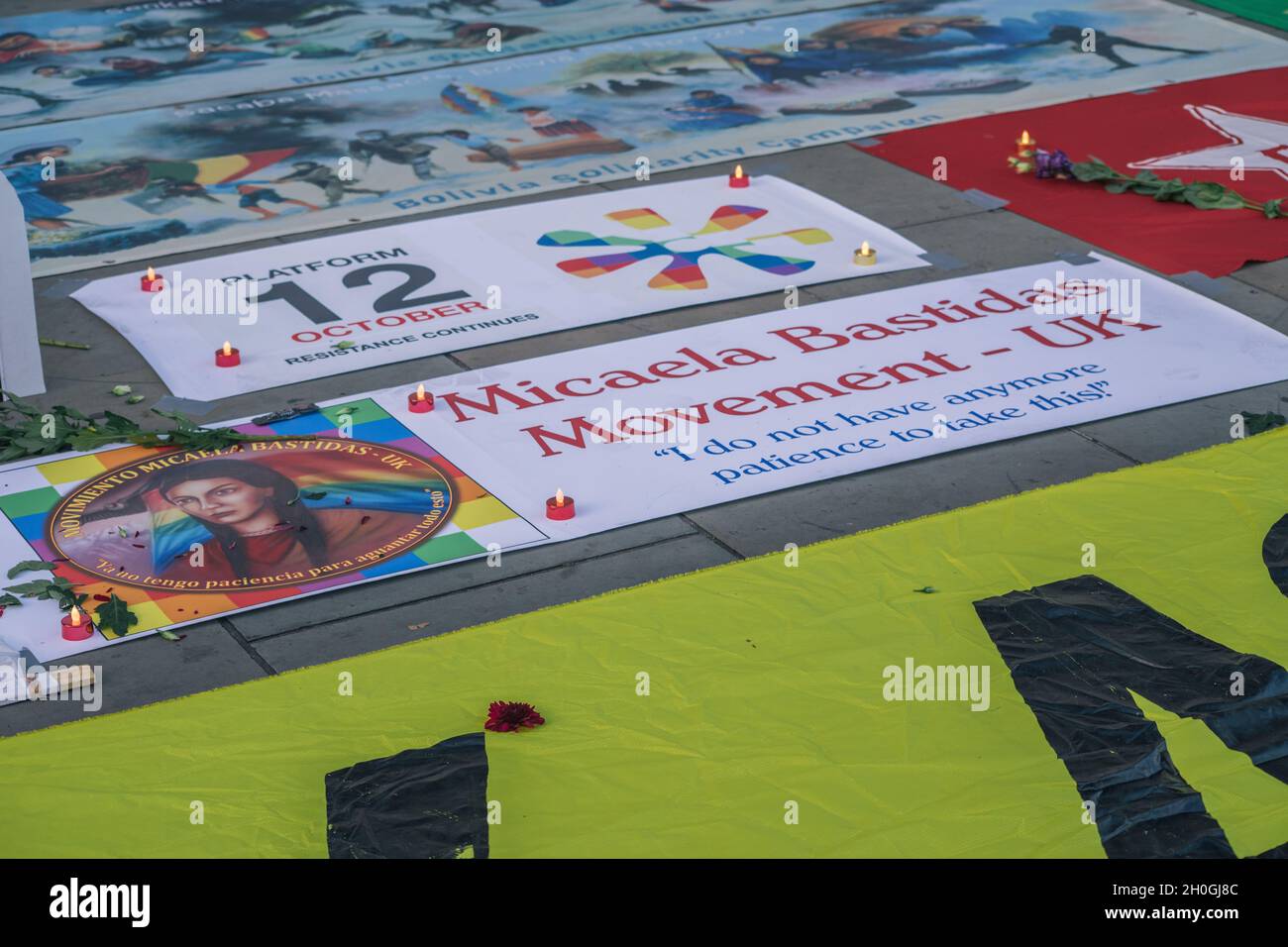 Trafalgar Square, London, England, Großbritannien 12. Oktober 2021 Columbus muss fallen! Neokolonialismus Muss Fallen! Indigene Völker protestieren gegen die Feier von Kolumbus. Symbolische Grabsteine mit den Namen und Bildern der Verstorbenen wurden auf dem Boden vor der Nationalgalerie aufgestellt, geschmückt mit Blumen und Kerzen. Im Anschluss an die Reden gab es eine Aufführung von Tänzern in indigenen Kostümen. Stockfoto