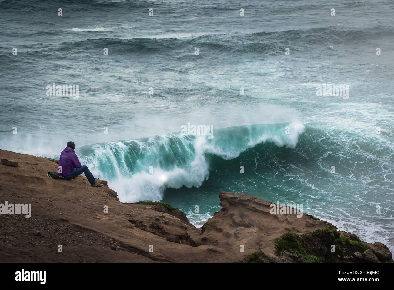 Mann, der die großen Wellen in Nazare beobachtet - Nazare, Portugal Stockfoto