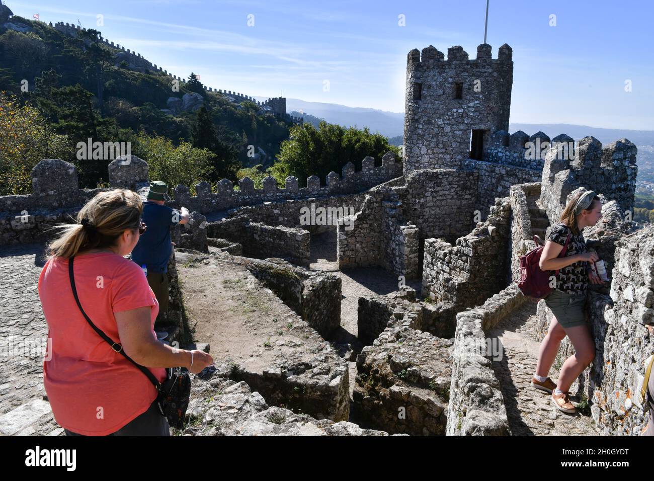 Die Menschen gehen durch die Befestigungslinie und die Türme innerhalb der Einrichtungen von Castelos dos Mouros. Das Castelo dos Mouros (maurische Burg), das von der UNESCO zum Weltkulturerbe erklärt wurde, verdankt seinen Namen der Vergangenheit der muslimischen Besatzung Portugals, die aufgrund ihrer optimalen Lage an der Spitze als strategischer Punkt mit vollem Blick auf die Umgebung dient. Die maurische Burg wurde 1154 von den Christen erobert. Im 19. Jahrhundert ordnete König Fernando II. Von Portugal seinen Wiederaufbau an, um ihn in die Gärten des Pena-Palastes zu integrieren, was die Bedeutung, die ihm genommen worden war, wieder aufnahm Stockfoto